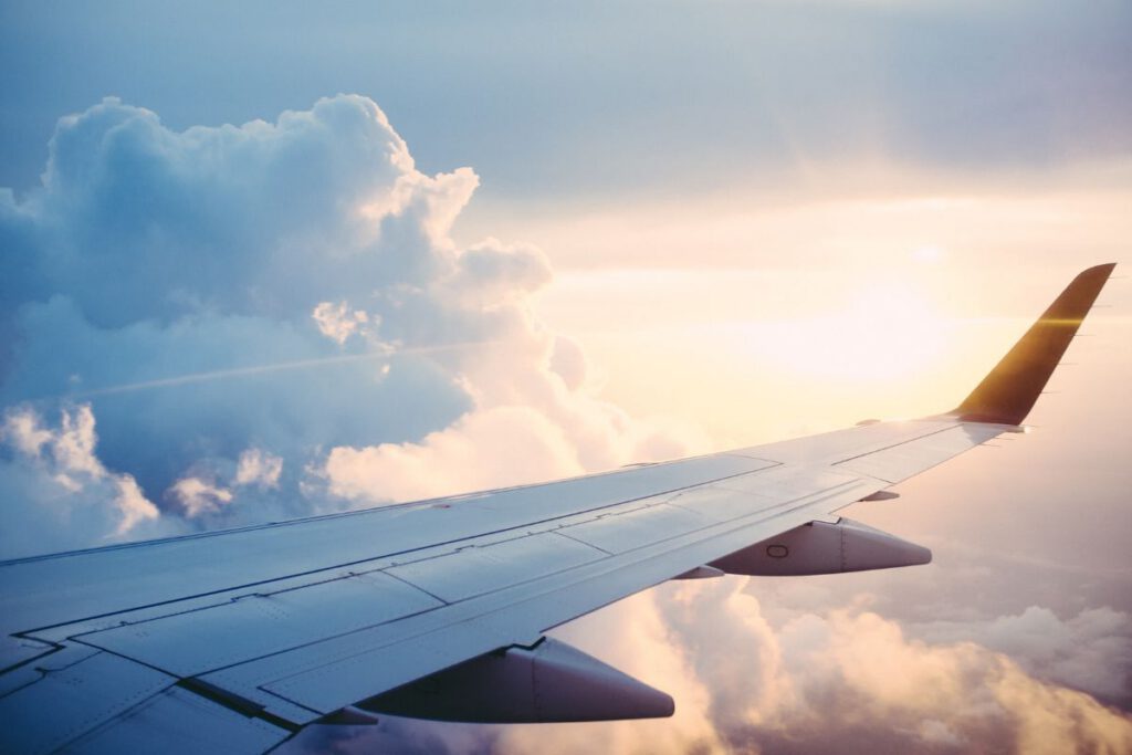 Looking out over an aeroplane wing with clouds and rays of sun behind